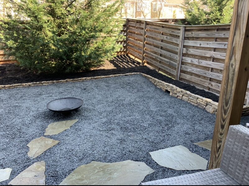Small townhouse backyard transformed with a three-sided stone wall and decorative crushed slate by Atlanta Waterscapes